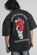 Person wearing a black oversize t-shirt with a graphic design on the back against a gray background