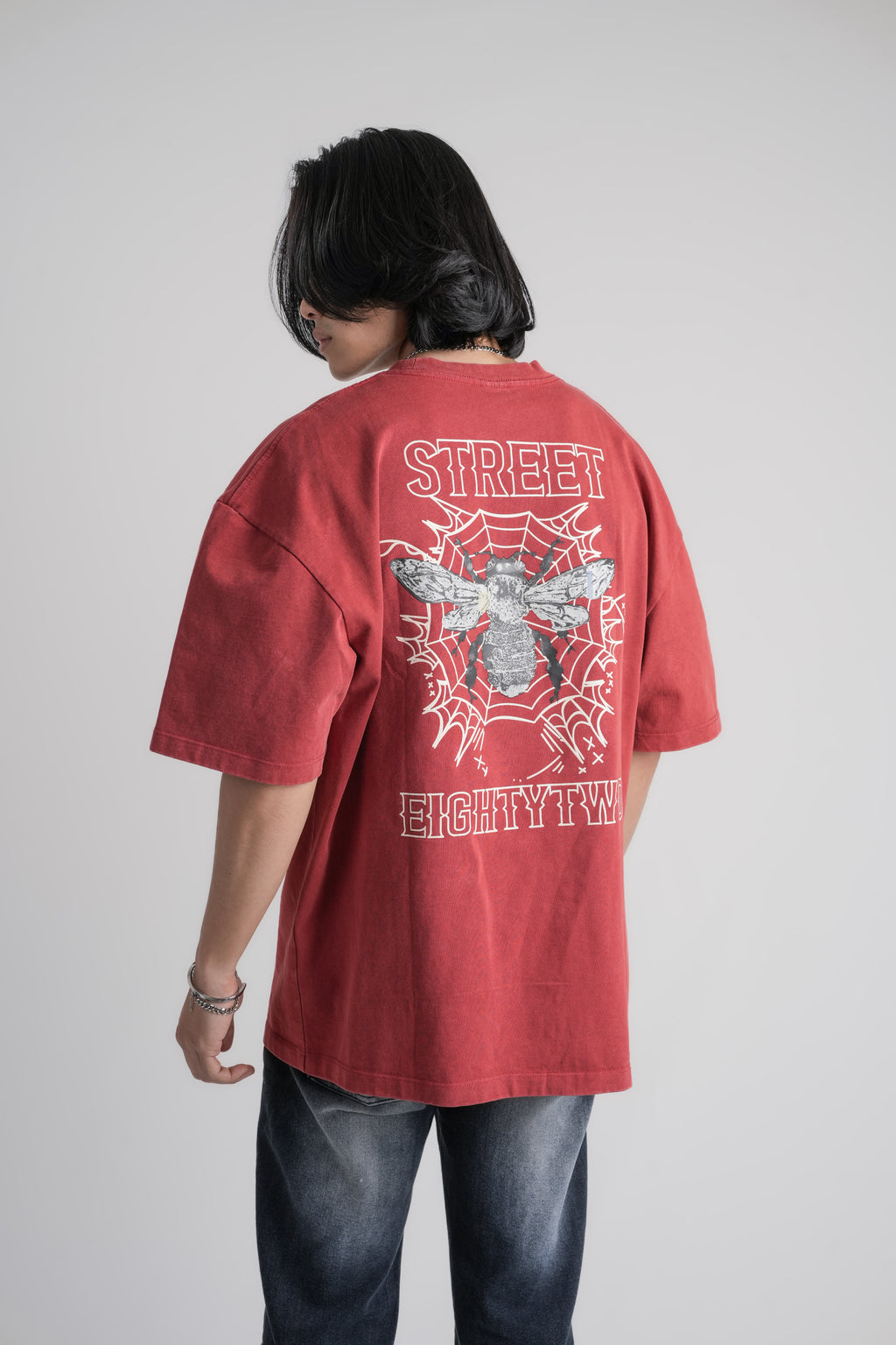 Person wearing a red over size t-shirt with a graphic design on the back against a plain background