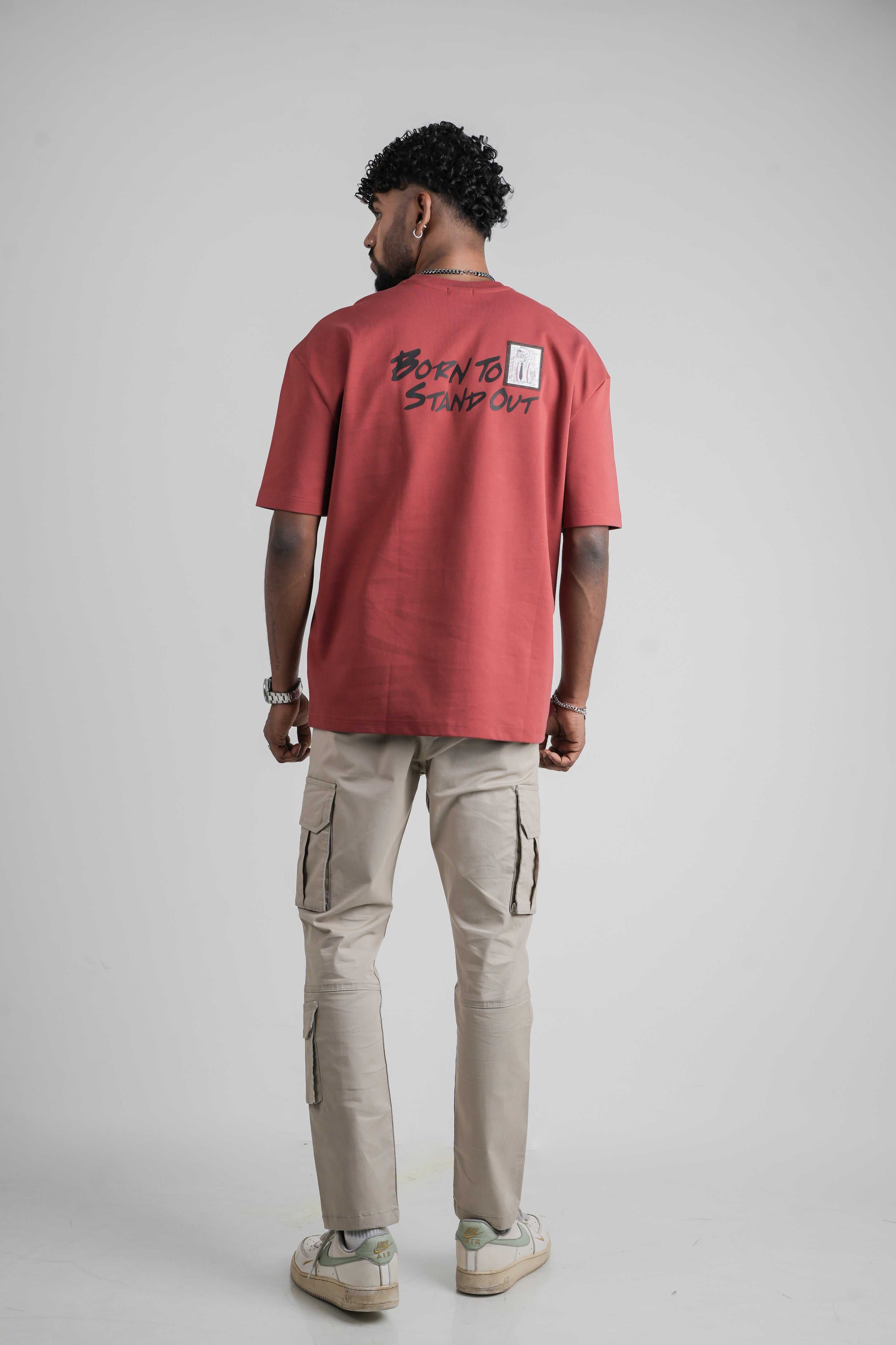 Person wearing a red oversize t-shirt with text on the back, standing against a plain background