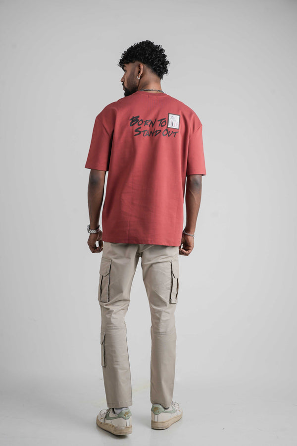 Person wearing a red oversize t-shirt with text on the back, standing against a plain background