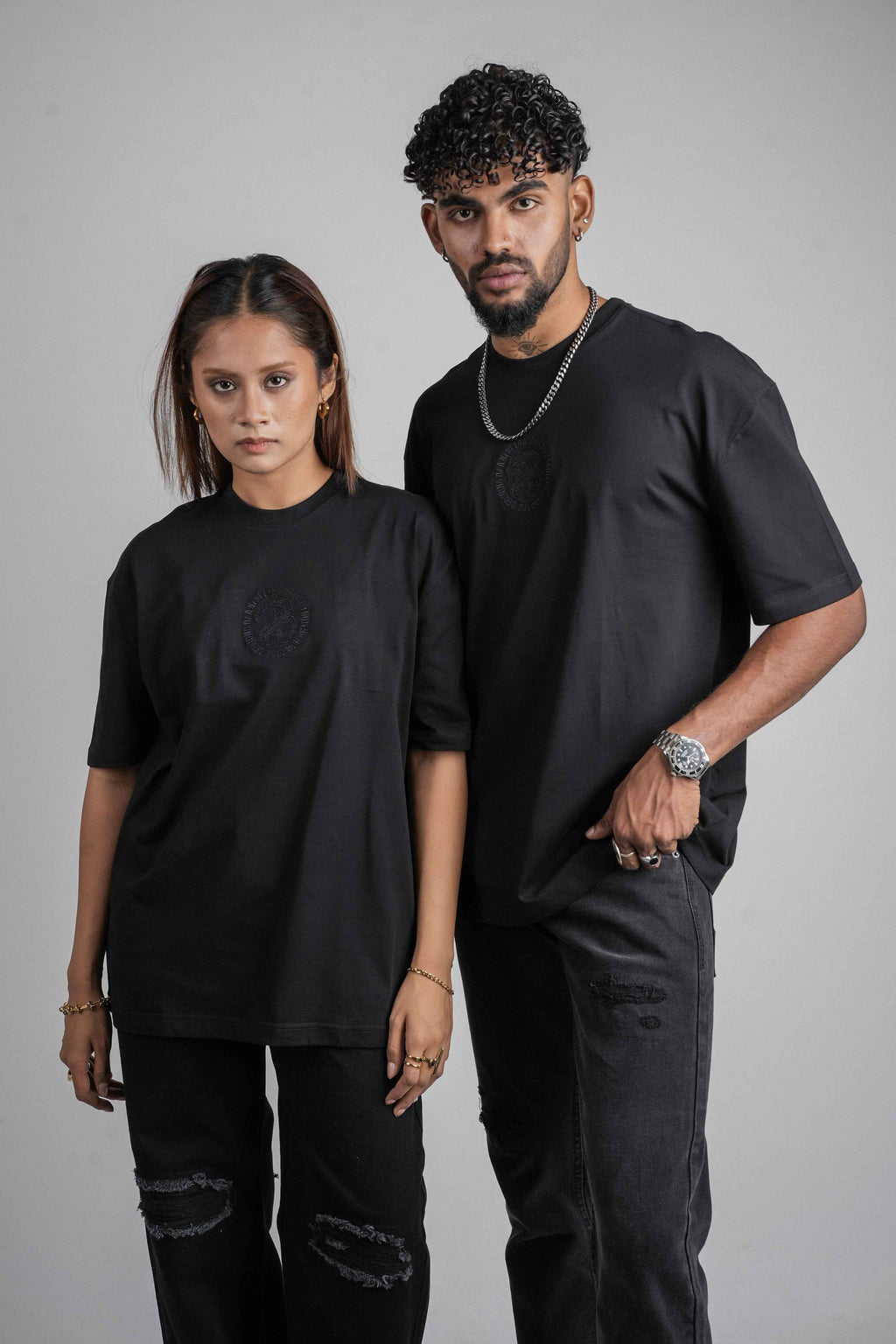 Two people wearing STREET82 oversize black t shirt outfits standing against a gray background