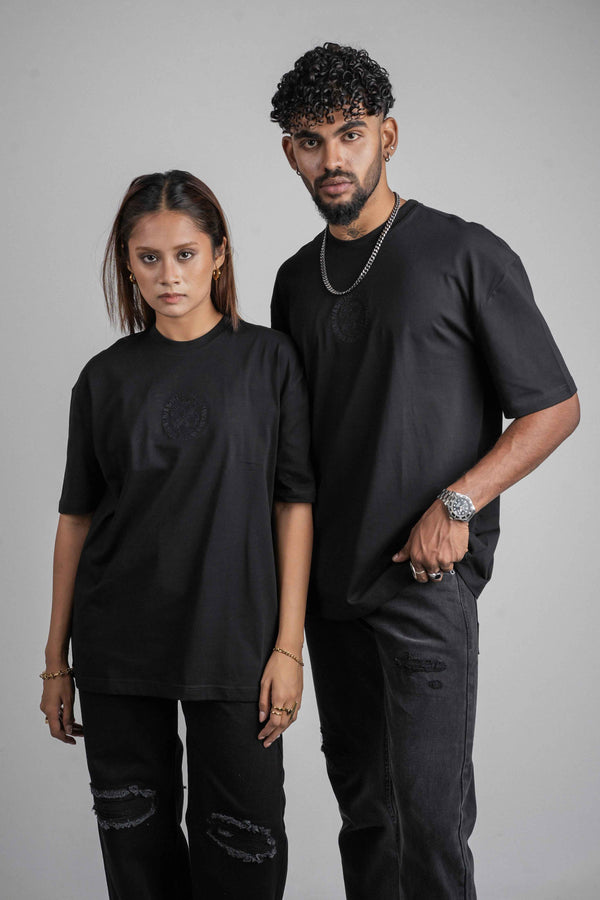 Two people wearing STREET82 oversize black t shirt outfits standing against a gray background