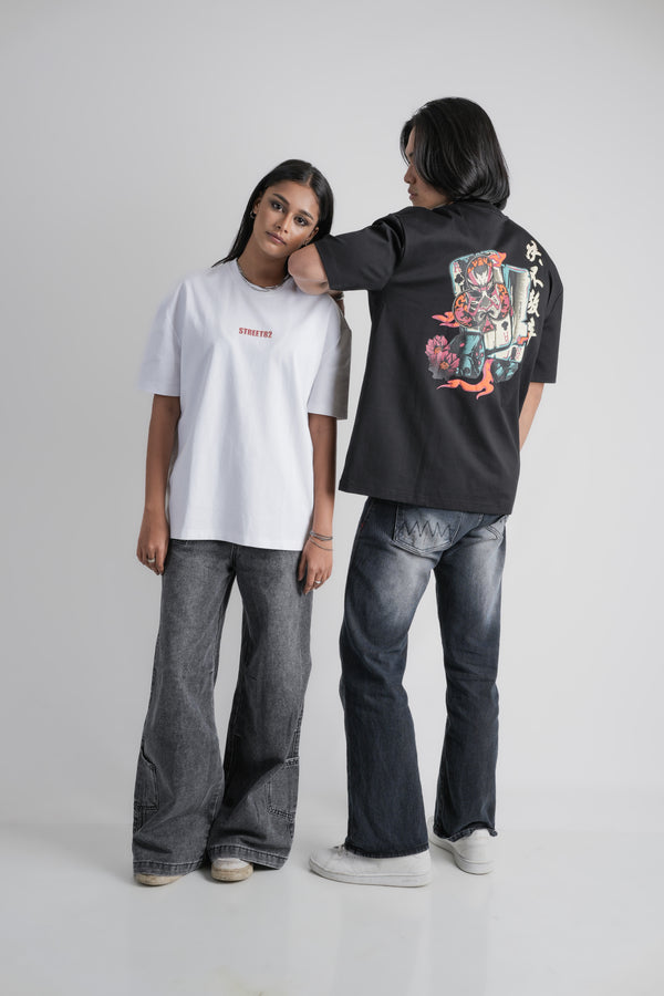 Two people wearing oversize t-shirts, one white with text and one black with colorful designs, standing against a plain background.